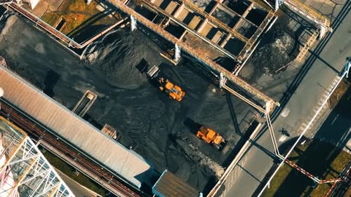 Aerial view of coal power plant with heavy machinery working on coal piles