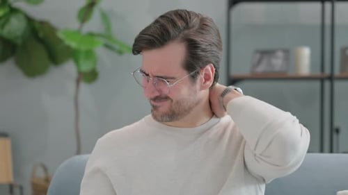 Man Rubs Stiff Neck in Close Up Indoors