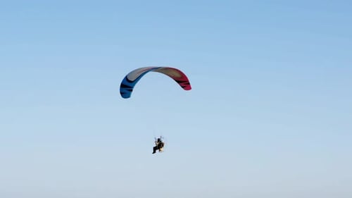 Powered Paraglider Flying Over the Ocean on a Sunny Day