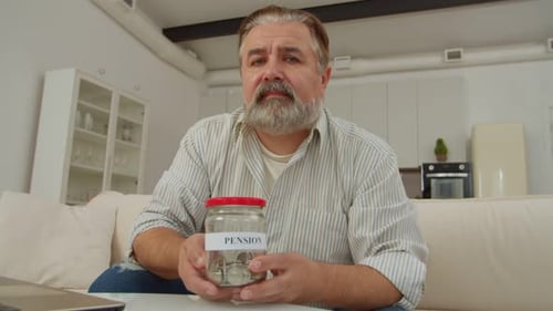 Mature Adult Holding Pension Jar At Home
