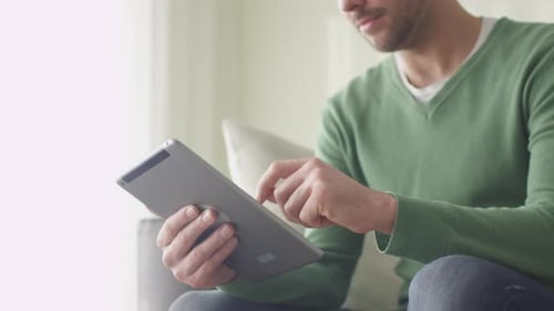 Man Relaxing at Home Using Tablet Device
