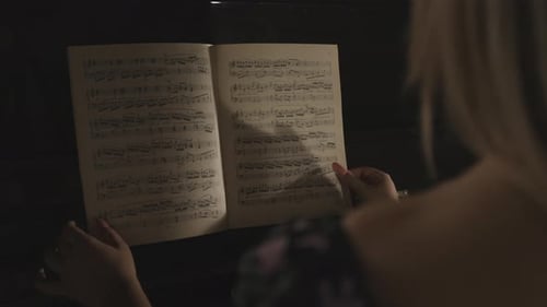 Partitura, cuaderno de notas musicales en papel, Vista Cinemática por encima del hombro de una mujer rubia caucásica