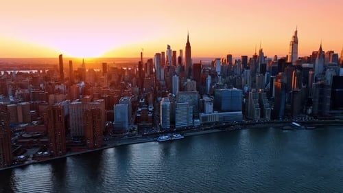 Orange light of golden hour illuminating the tops of skyscrapers in New York.