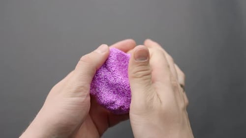 Close-up of hands squishing purple Floam slime in satisfying sensory play