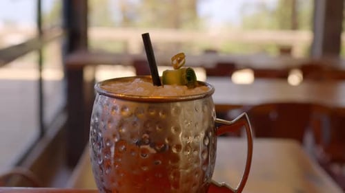 close up video of a drink served in a cold metal glass with cucumbers and lemon
