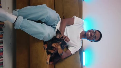 Young Adult Lying on Couch Petting Dog