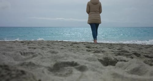 Woman walking into the sea from the beach, captured from below