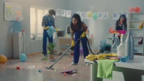 Grupo de faxineiros limpa o escritório depois de uma festa Corporativo Uma mulher afro-americana e asiática