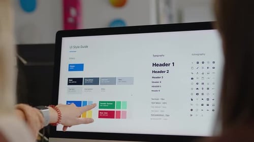 Corporate graphic designer coworkers look at a font and color branding sheet on a computer screen po