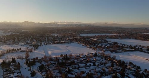 Drone shot of the sun setting over the Rocky Mountains in Denver, CO on a snowy winter day.