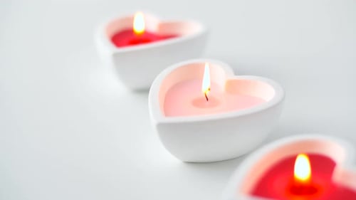 Heart Shaped Candles Burning on White Background