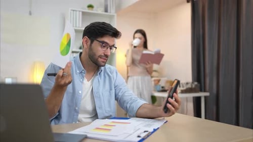 Man Presents Charts on Video Call in Home Office