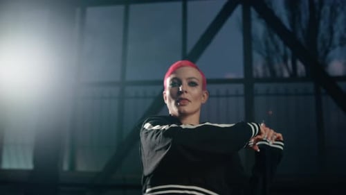 Nahaufnahme: Stilvolle Künstlerin, Performerin, schaut Kamera beim Tanzkurs im Dunkeln