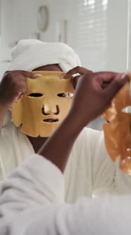 Vertical of Woman Applying Sheet Mask on Face by Mirror