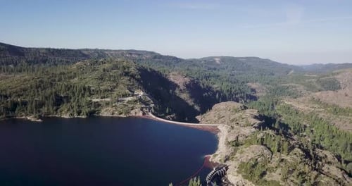 Lake with blue water surrounded by rocky Mountains pine trees redwood move forward