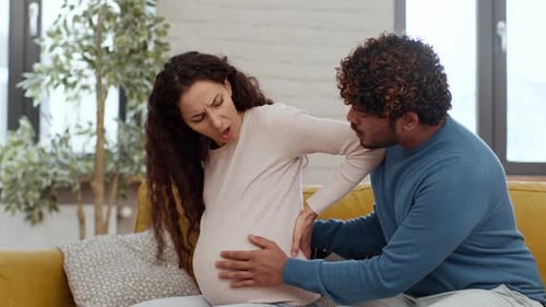Man Massaging Back of Pregnant Woman in Home