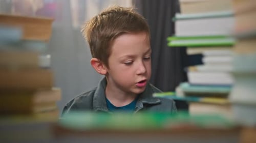 Young Boy Looks Between Stacks of Books