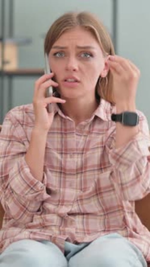 Woman Anxiously Talking on Cellphone Indoors
