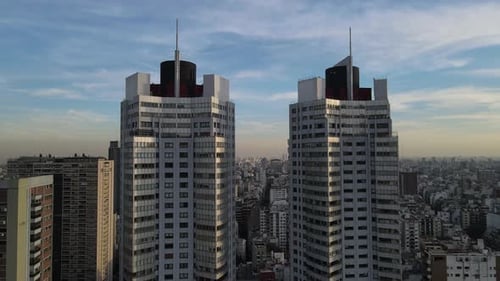 Aerial view of Twin Skyscraper Buildings in Buenos Aires and cityscape in background during golden h