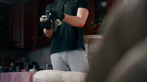 Man Cleaning Couch Cushion with Cleaner and Sponge