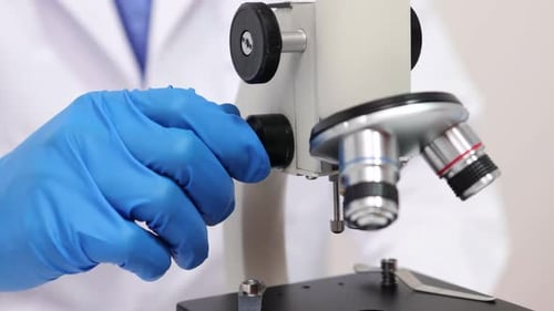 A scientist works tirelessly in a lab examines samples through a microscope, highlighting advances