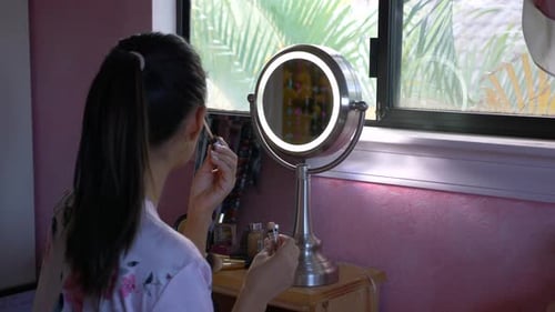 Frau schminkt sich vor dem Schminkspiegel, während die Kamera nach links gleitet.