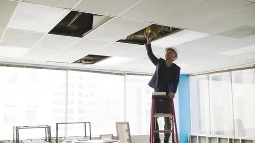 Architect Looking at Wiring in Ceiling of Empty Office Space Adult