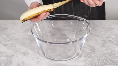 Smashing Riped Bananas in a Glass Mixing Bowl to Prepare Coconut Banana Pancakes