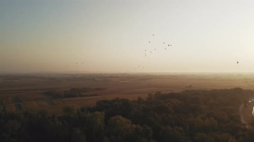 Stunning 4K aerial footage of a drone filming hot air balloons. Flying over farming fields and river
