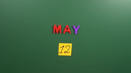 Hand sticking a sticker 12 May calendar day on school board. 12 date of May. Twelfth day May