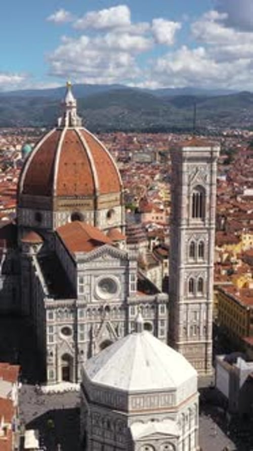 Vertical drone spinning around Cathedral of Santa Maria del Fiore and city on a sunny day in