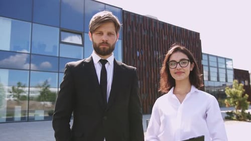 Portrait of Caucasian Businessman and Businesswoman in Formal Wear Posing Near Modern Glass Building