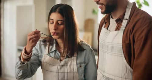 Couple Cooking and Tasting Food in Kitchen