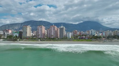 Aerial Video of Expanding Coastal City Towers Rising Beside Beachfront With Surf Crashing and