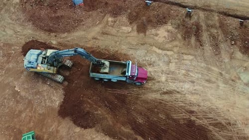 Excavator Loads Soil into Dump Truck Aerial