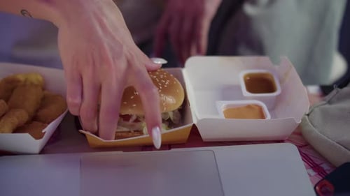 Woman Eating a Burger with Chicken Nuggets