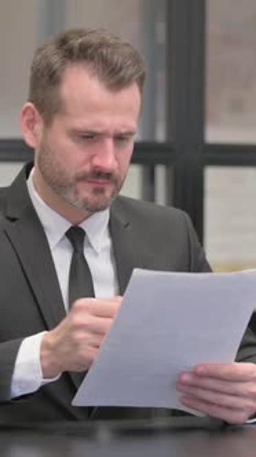 Thoughtful man reviews documents in professional setting