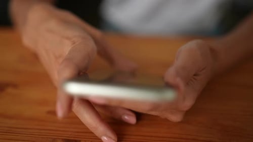 Closeup Highangle View of Unrecognizable Young Woman Using Smartphone Texting Messages Sitting at