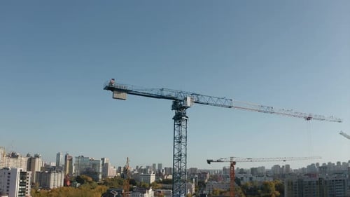 Vista superior de la grúa de construcción sobre el fondo de la ciudad en un día soleado. Imágenes de archivo. Grúa de construcción
