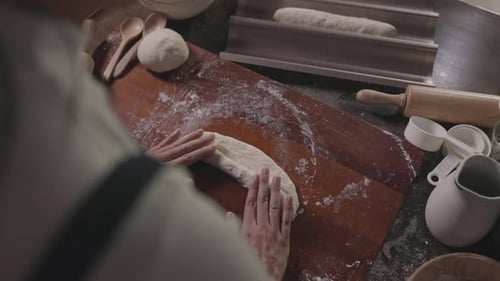 Chef rolls a ball of dough to hand make bread at bakery