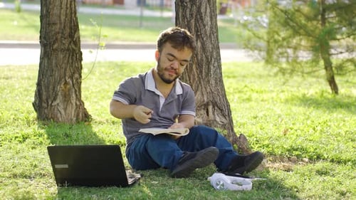Tired college dwarf student studying outdoors.