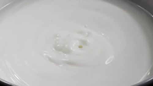 Gota de leite caindo e espirrando; deixando lindas ondulações redondas na superfície do leite.