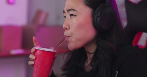 Asian, woman and gamer at computer eating and drinking with focus for game