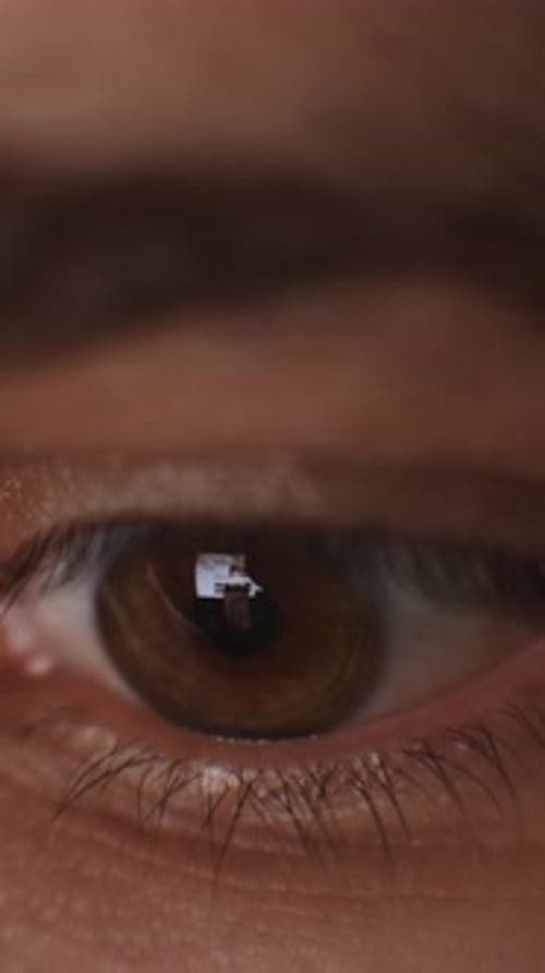 Extreme Nahaufnahme eines menschlichen braunen Auges, das sich weiter öffnet und eine detaillierte Irisstruktur enthüllt