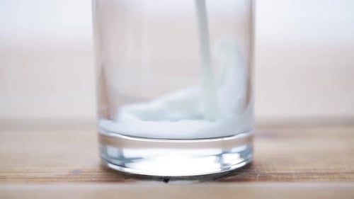 Healthy Eating, Diet and Drinks Concept - Milk Pouring Into Empty Glass
