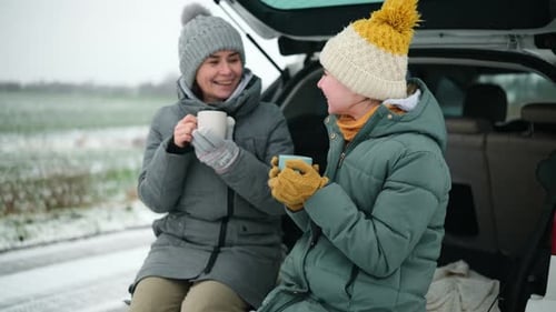 Mother and Teen Daughter Enjoying Hot Drinks in Winter
