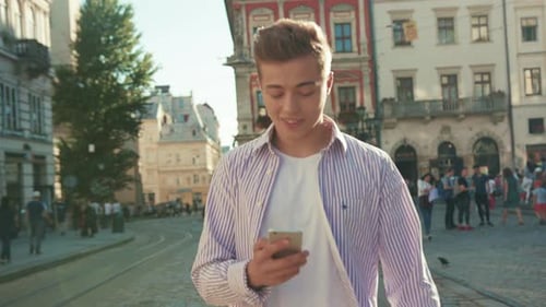 Portrait Young Happy Man Walk on Street Use Phone Look Around Smile Sunlight Cute Work Mobile Gadget