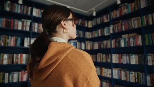 Teenagerin wählt Buch in der modernen Bibliothek