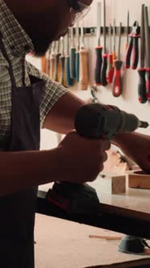 Vertical Video Craftsperson Sinks Screws Into Wood Block with Electric Tool