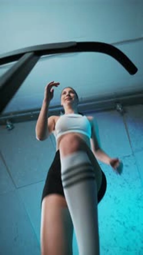 Retrato de una joven y enérgica chica de fitness con top blanco y pantalones cortos negros haciendo ejercicios saltando sobre mo